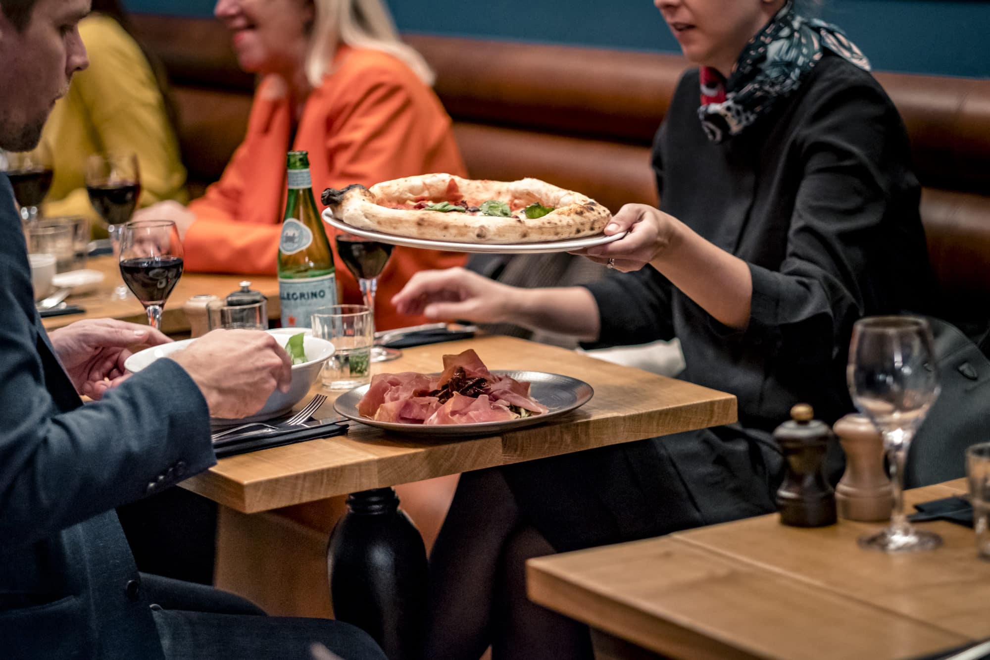 Serveuse apportant une pizza napolitaine et une assiette de charcuterie