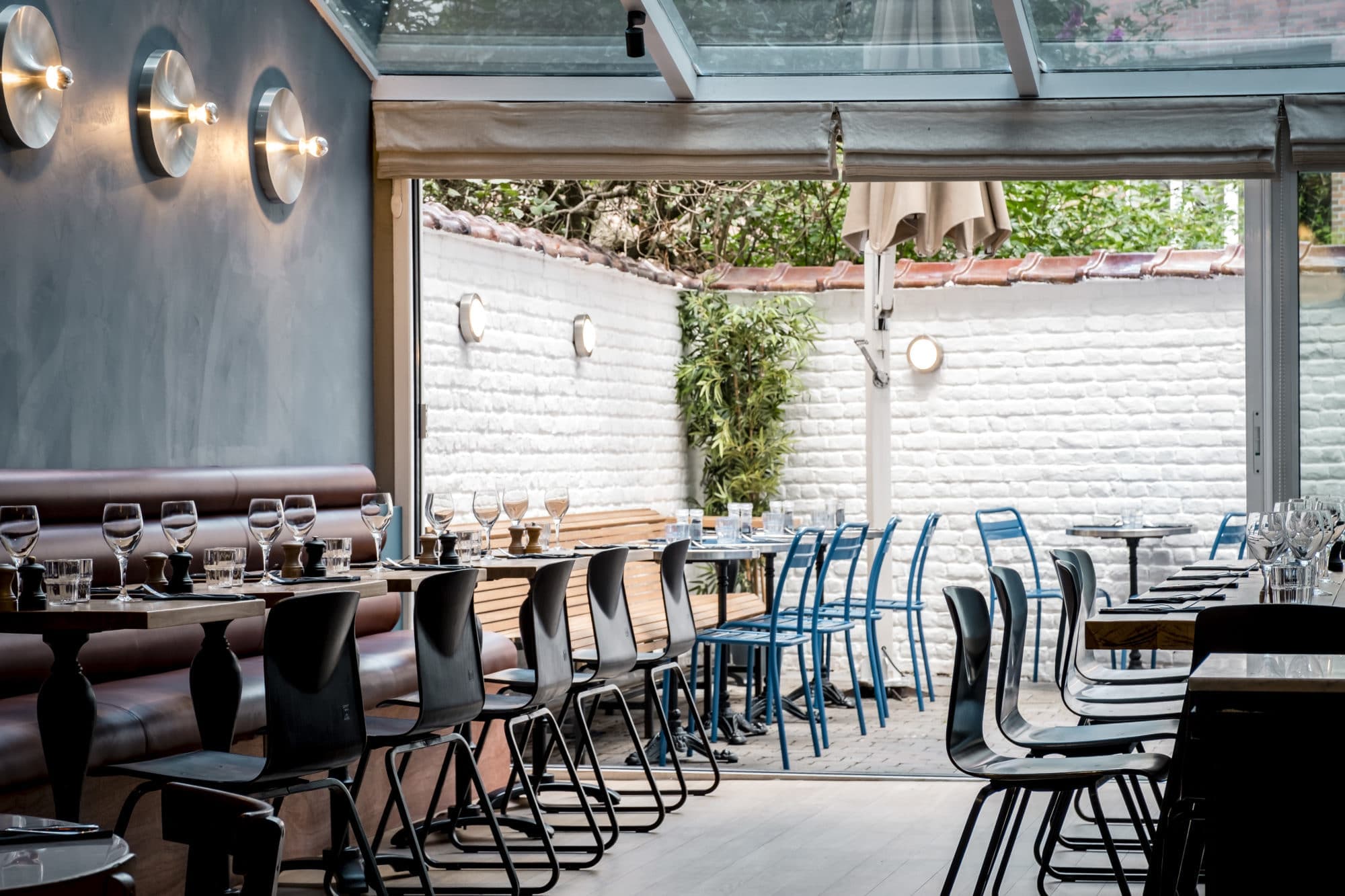 Salle véranda de MiTo ouverte sur la terrasse et le mur de briques blanches