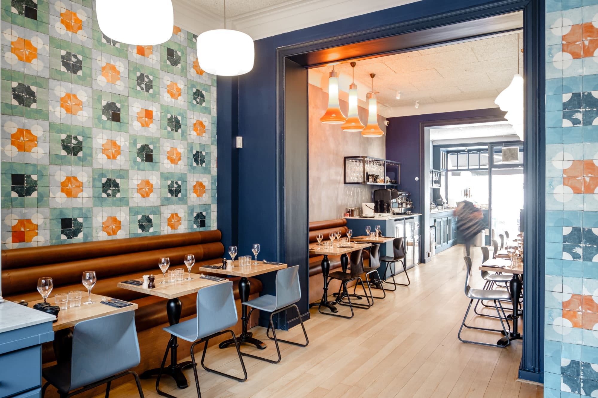 Salle avec mur d'azulejos colorés, banquette cognac et coin bar